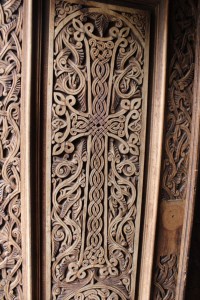 An ornate door seen in Armenia. It's wood surface carved into winding patterns that form a cross and snake-like patterns. 