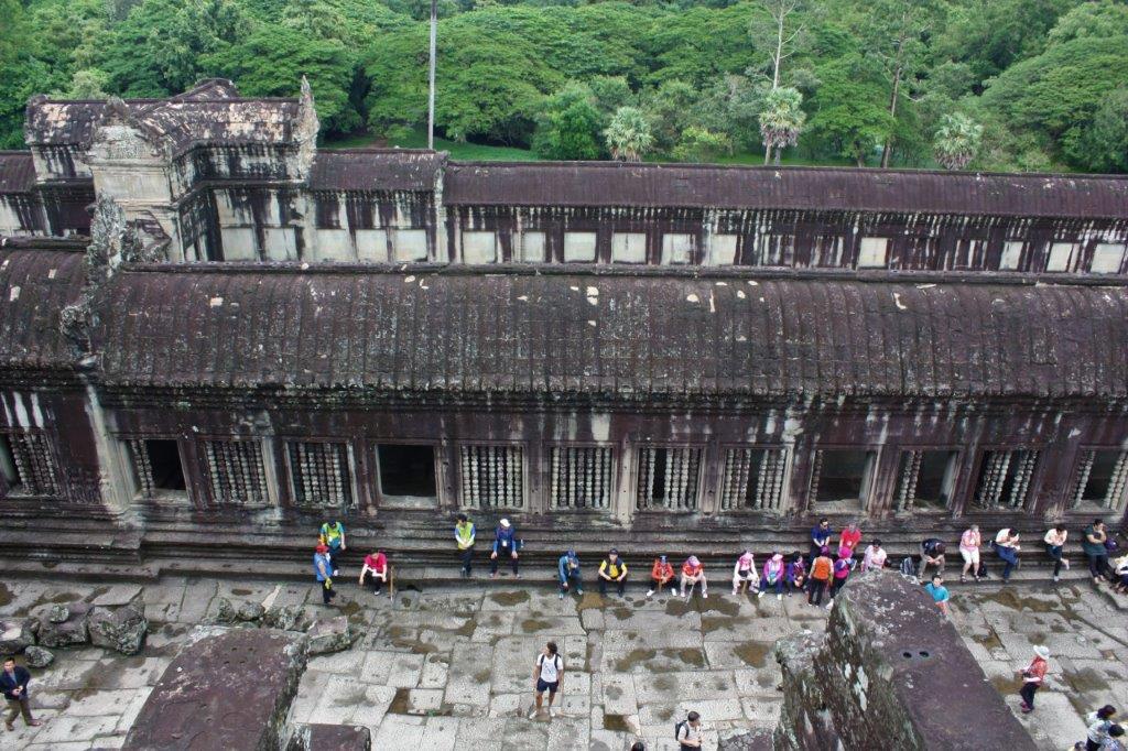 A photograph taken from upstairs in Angkor Wat, looking down at the wall and jungle beyond. 