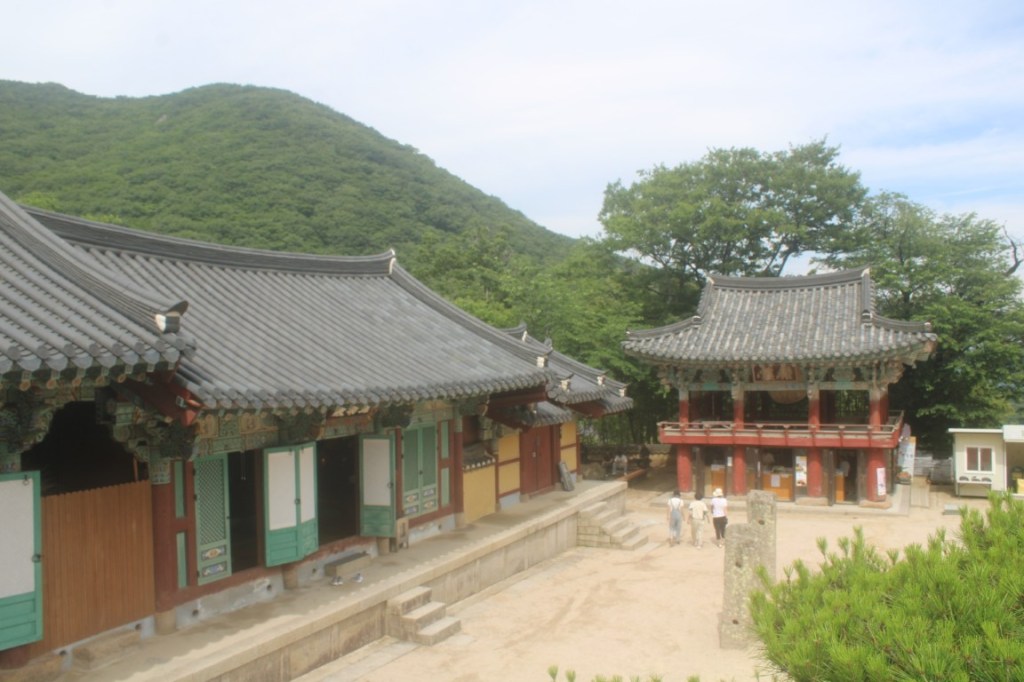 At photograph with a hill in the left background and a drum tower in the right foreground. Taken at Beomeosa Temple outside Busan, South Korea.