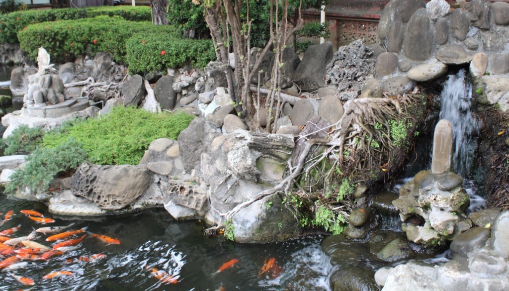 Photograph taken in Chihkan Culture Park in Tainan, Taiwan, featuring a rocky garden, koi pond, and waterfall.