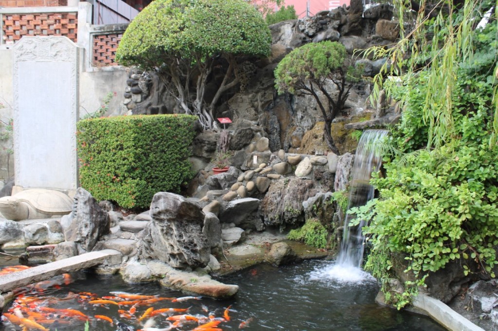 Photograph taken in Chihkan Culture Park in Tainan, Taiwan, featuring a rocky garden, koi pond, and waterfall.