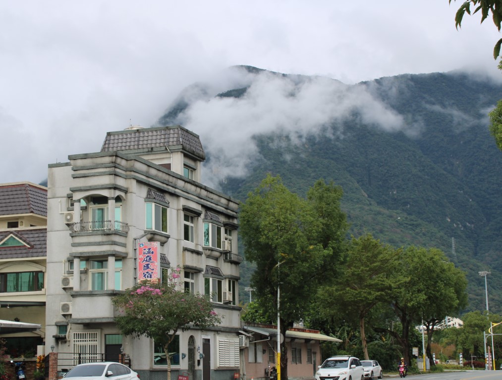 Photograph of a Hualien street scene with a backdrop of green cloud-enshrouded mountains. 