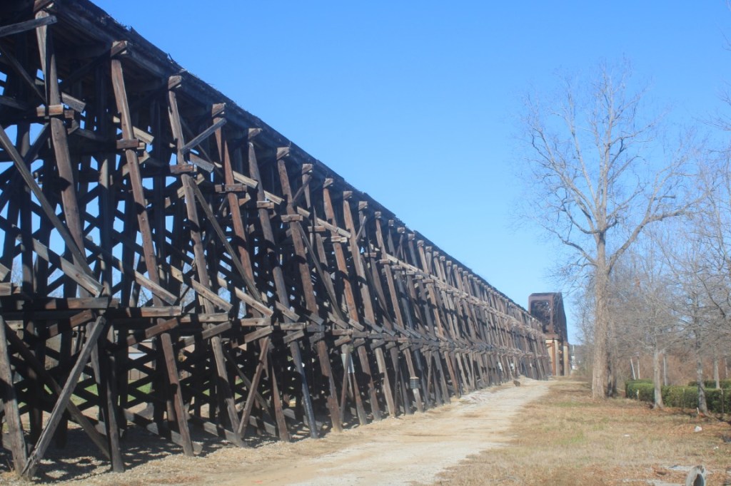 Photograph of the railway bridge over the Black Warrior River from the Tuscaloosa Riverwalk Park of Tuscaloosa, Alabama.