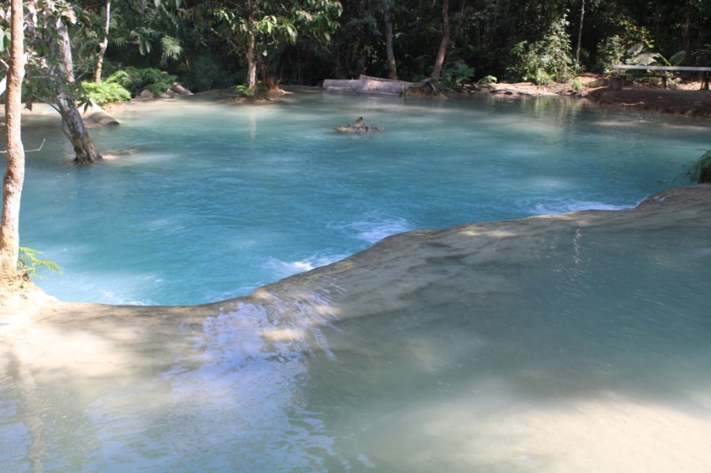 Photograph of teal water at one of the terraced drop offs of Kuang Si waterfall in Laos.