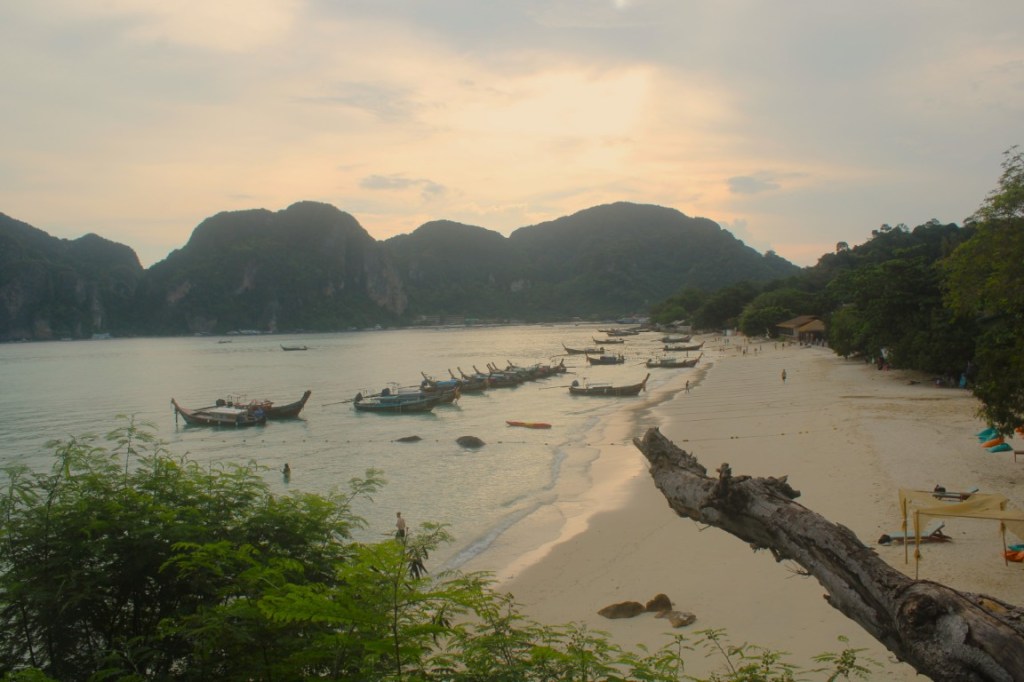 Photograph of Ton Sai Beach of Koh Phi Phi, Thailand at sunset with small boats arrayed along the shore. 