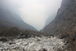 Photograph of a streambed and cloudy mountains take on the Annapurna Sactuary Trek in Nepal.