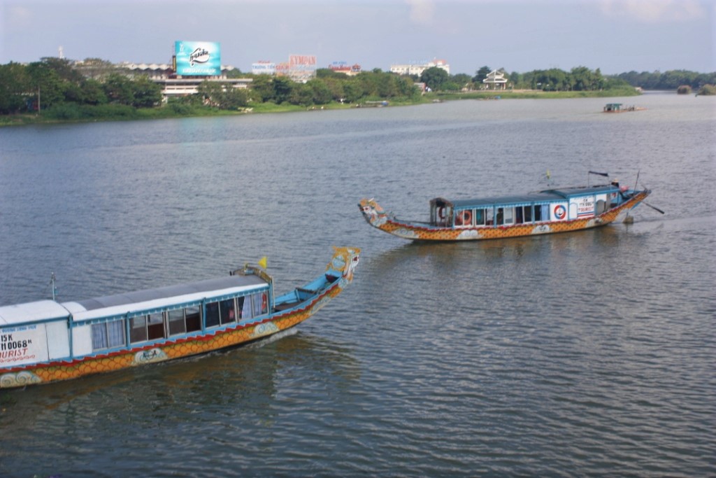 Photograph showing two ornate ferries on the Perfume River as it runs through Huế, Vietnam.