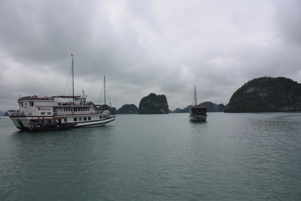 Photograph taken in Bai Tu Long Bay in Northern Vietnam of boats, islands, and cloudy skies. 