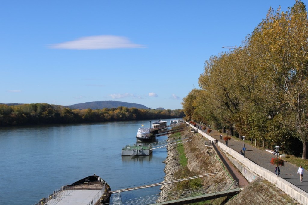Photograph of the riverwalk and docked boats on the Danube River taken from the Most SNP bridge in Bratislava, Slovakia.