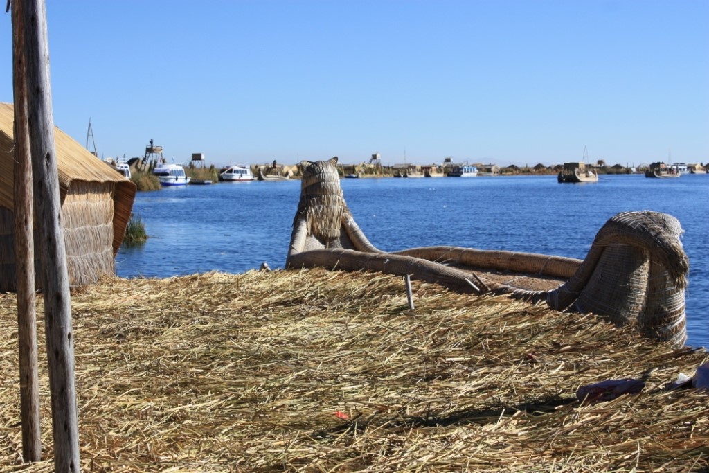 Photograph taken on one of the Uros floating islands of Lake Titicaca with a reed boat along the island's edge.