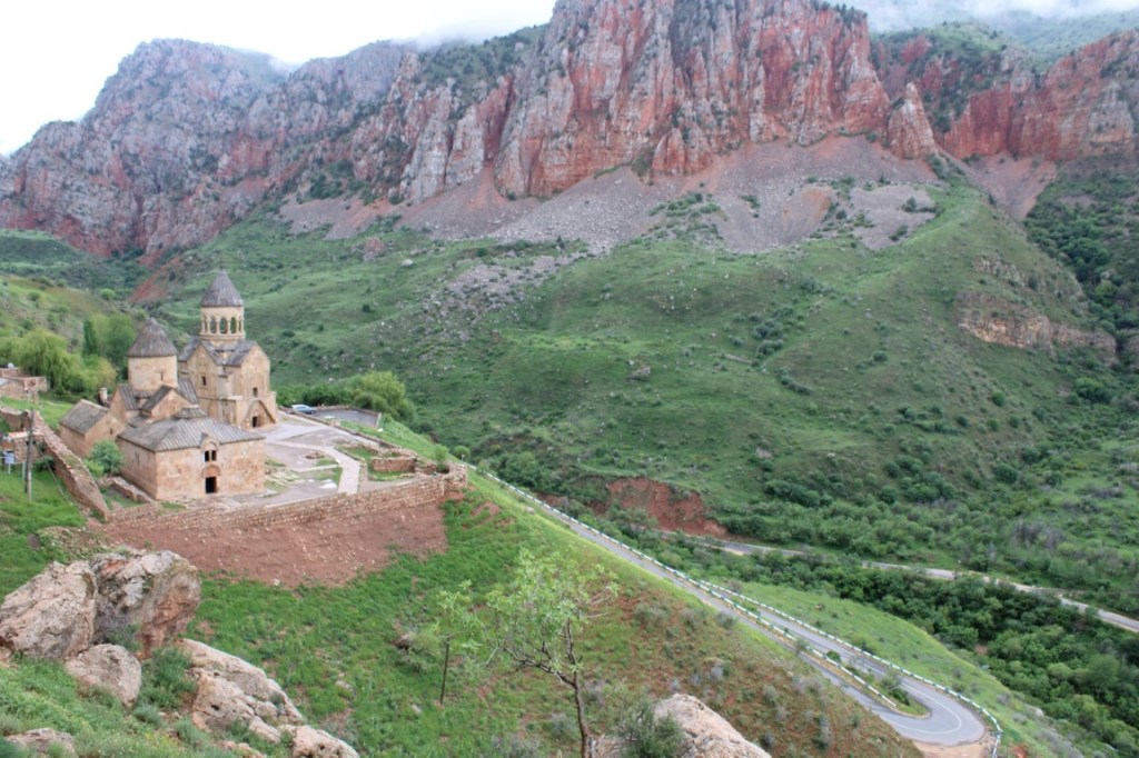Photograph of Noravank Monastery in Armenia with red cliffs looming across the way.