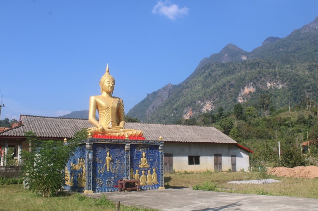 Photograph of a Golden Buddha with a backdrop of Karst mountains and blue sky that was taken on the "Blue Lagoon" loop to the west of Vang Vieng, Laos.