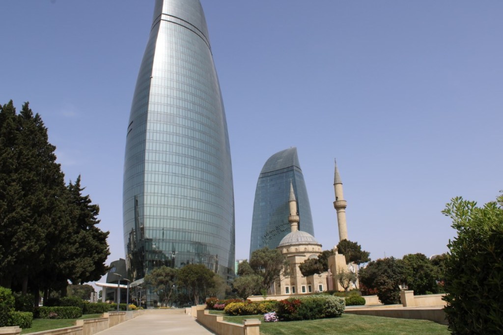Photograph of the Hazi Aslanov Grave Memorial, and the Flame Tower's that loom over it. Taken in Baku, Azerbaijan.