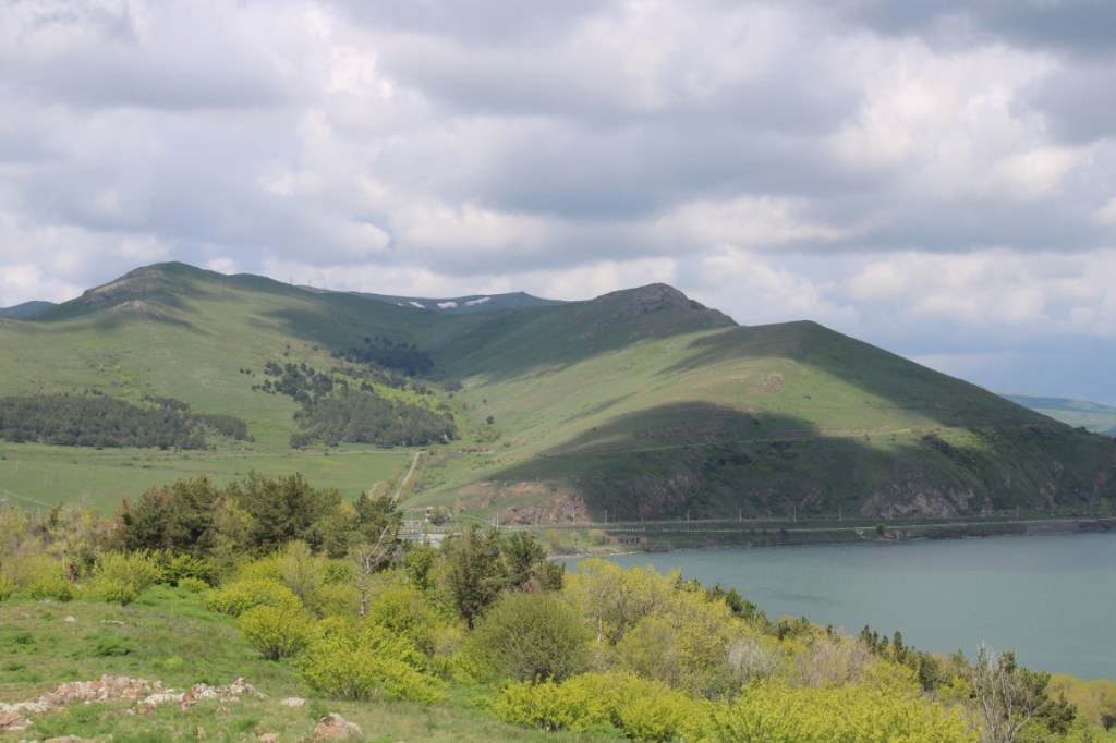 Photograph taken at Sevanavank beside Sevan Lake in northern Armenia. It shows a green mountain mottled by cloud shadows.