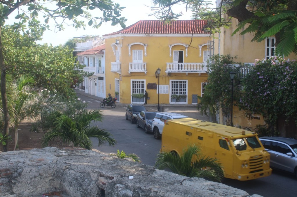 Photograph of Cartagena with a building and an armored car in school bus yellow.