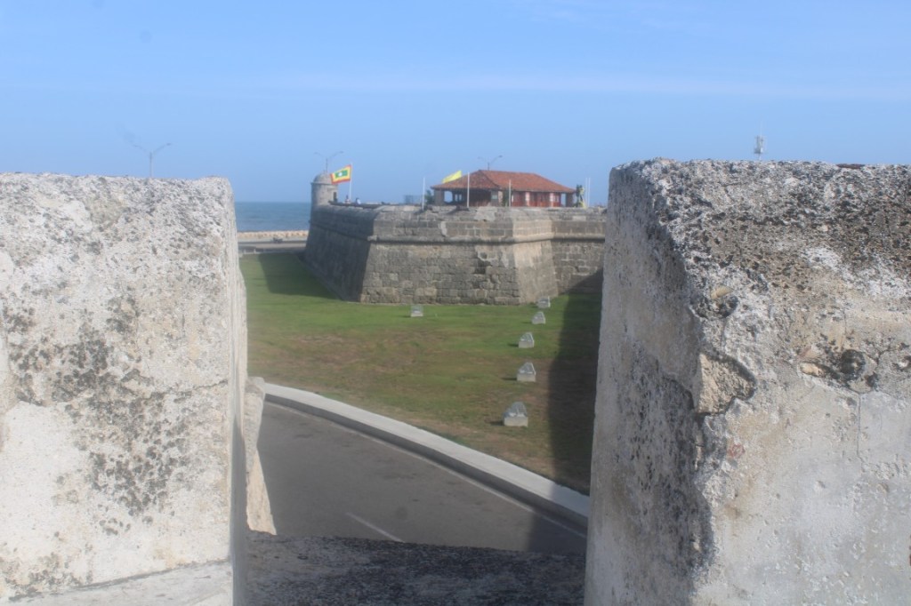 Photograph of the Cartagena City Wall (Baluarte de Santo Domingo) with a glimpse of sea beyond. 