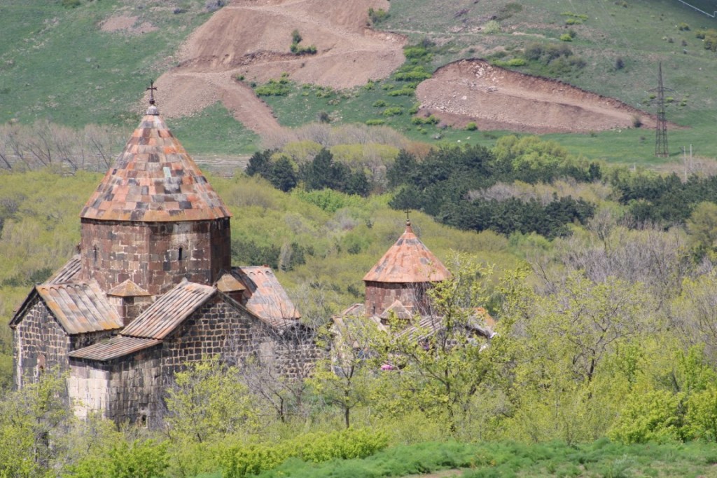 Photograph of the Sevanavank Monastery chapel fringed with vegetation and with a hillside as backdrop.